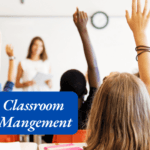 A female teacher in front of students in a classroom and all students are engaged and raising their hands.