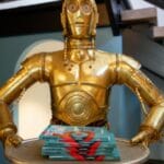 a star wars action figure holding a tray of books