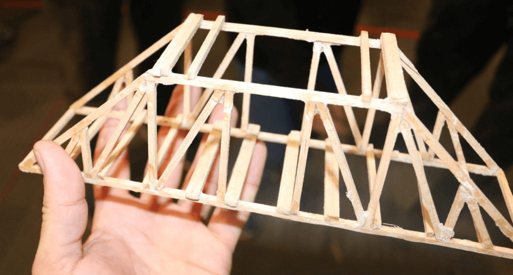 Someone is holding a balsawood bridge