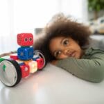 boy lying on bed playing with red and blue toy truck