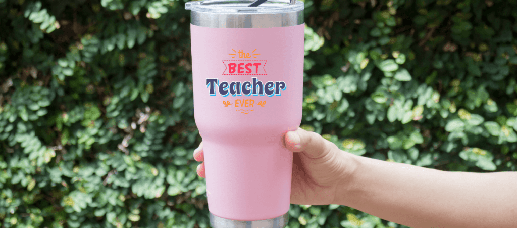 Someone is holding a pink tumbler and best teacher ever says on this item.