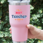 Someone is holding a pink tumbler and best teacher ever says on this item.