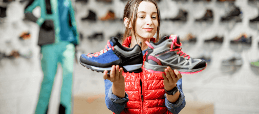 A girl is holding two sport shoes.