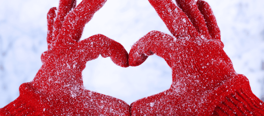 a person in snow gloves making a heart shape