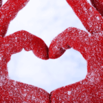 a person in snow gloves making a heart shape